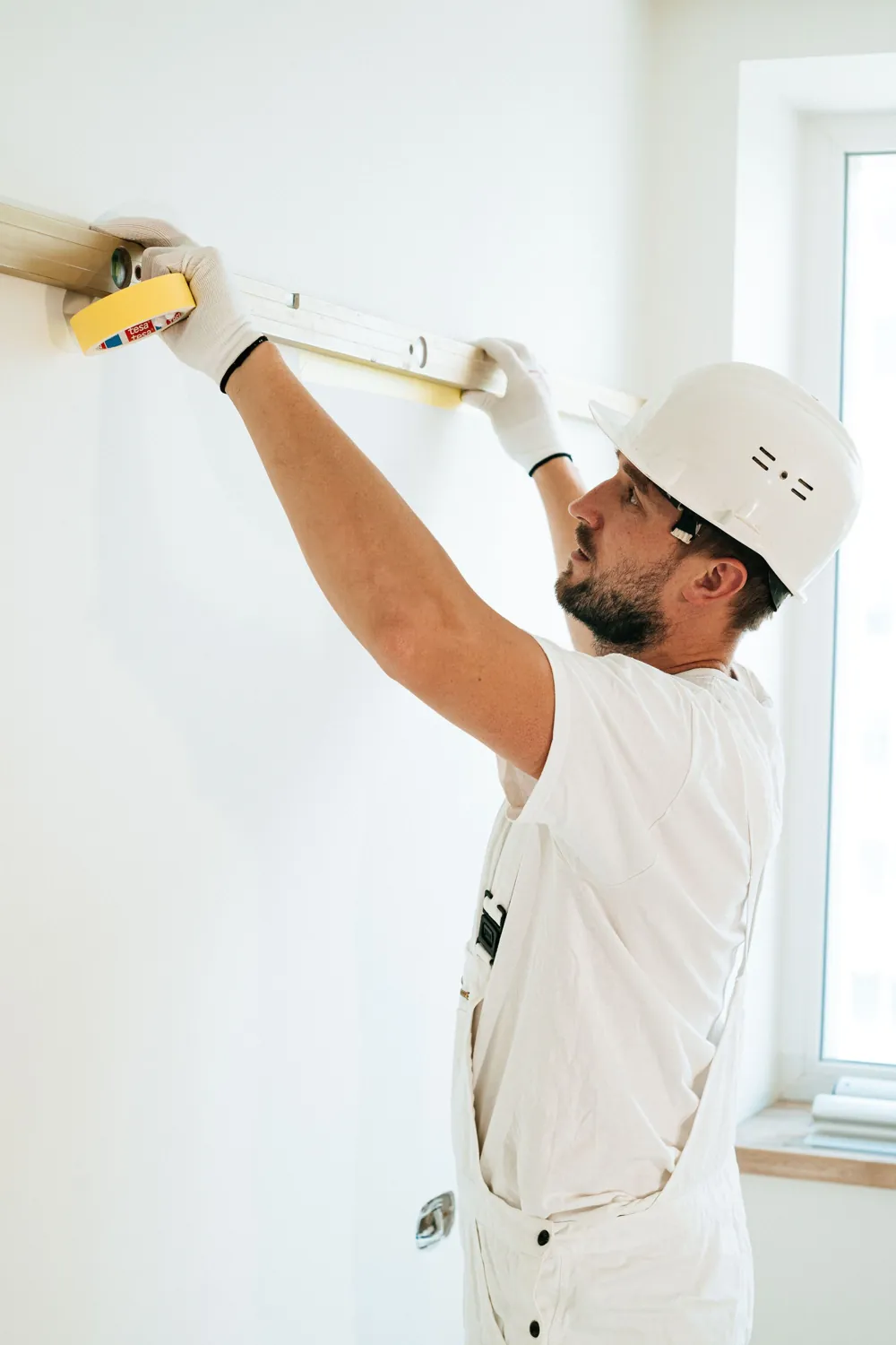 A tradesperson measuring a wall with a tape measure